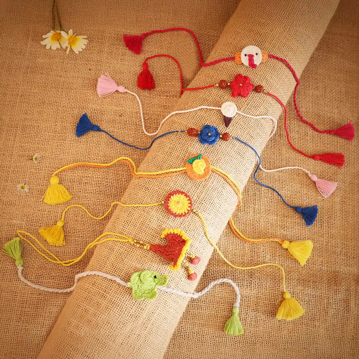 Handmade Crochet Multicolor Family Rakhi With Roli Chawal Set Of 8 - Overhead view of multiple Rakhis
