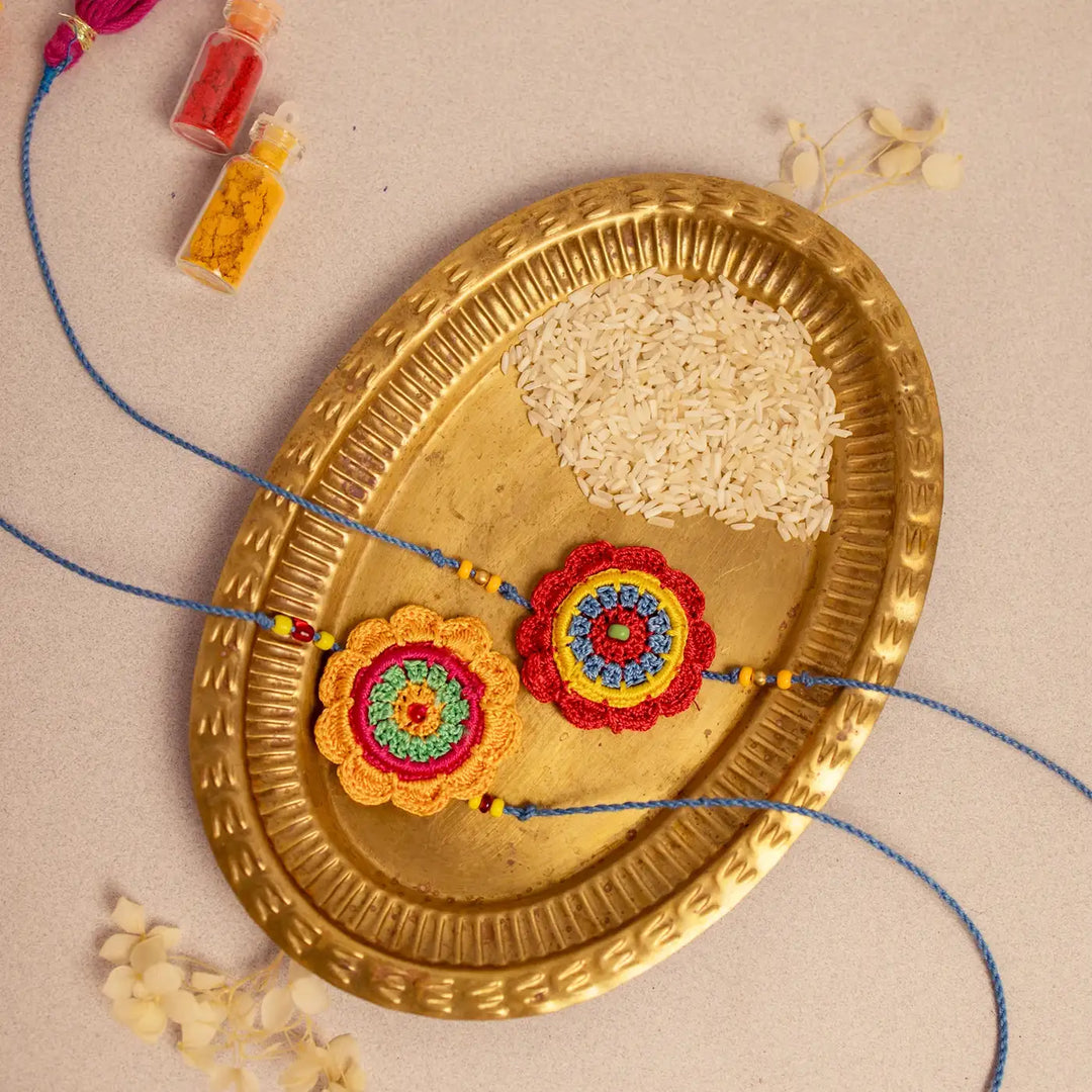 Handmade Crochet Noor Rakhi With Roli Chawal Set Of 2 - Styled with Color Powders and Rice