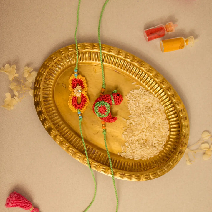Handmade Crochet Paakhi And Phool Rakhi With Roli Chawal Set Of 2 - Side view of arranged Rakhis