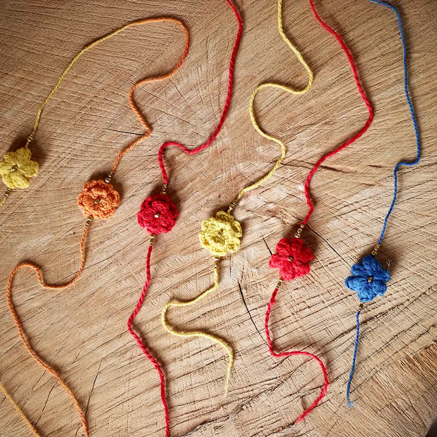 Handmade Crochet Moti Flower Rakhi With Roli Chawal Set Of 6 - Flat Lay Display of Multiple Bracelets