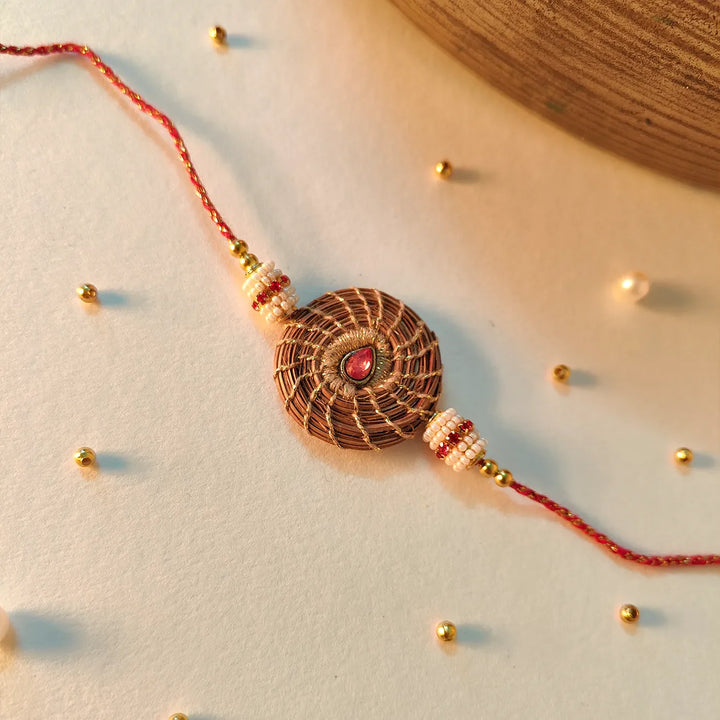 Eco Friendly Handmade Red Stone Pine Needle Rakhi With Pouch And Roli Chawal - Artistic Styled Flat Lay