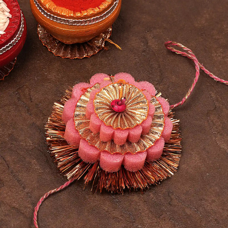 Handmade Layered Pink And Golden Foam Rakhi With Roli Chawal - Angled Close-up View