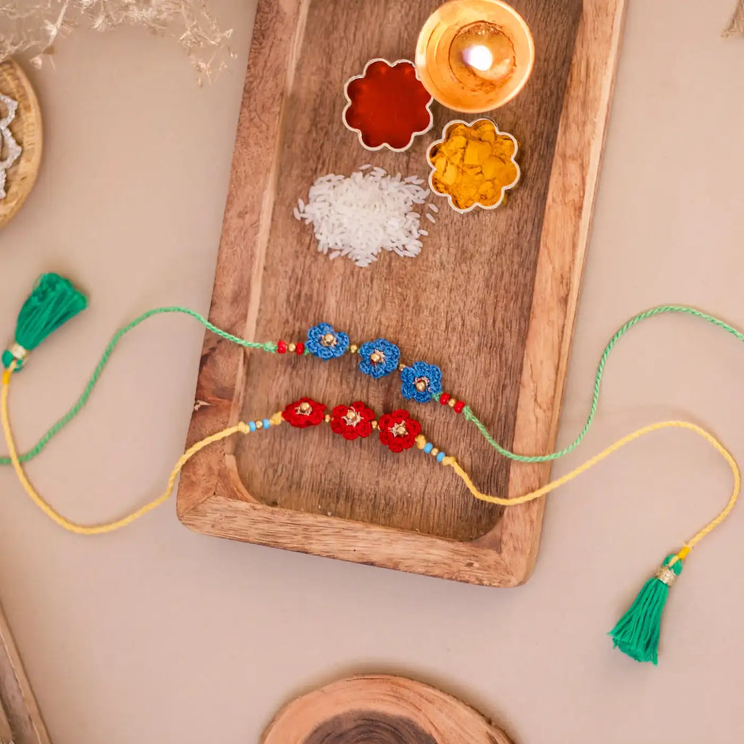 Handmade Crochet Red And Blue Floral Rakhi With Roli Chawal Set Of 2 - Styled with Traditional Elements
