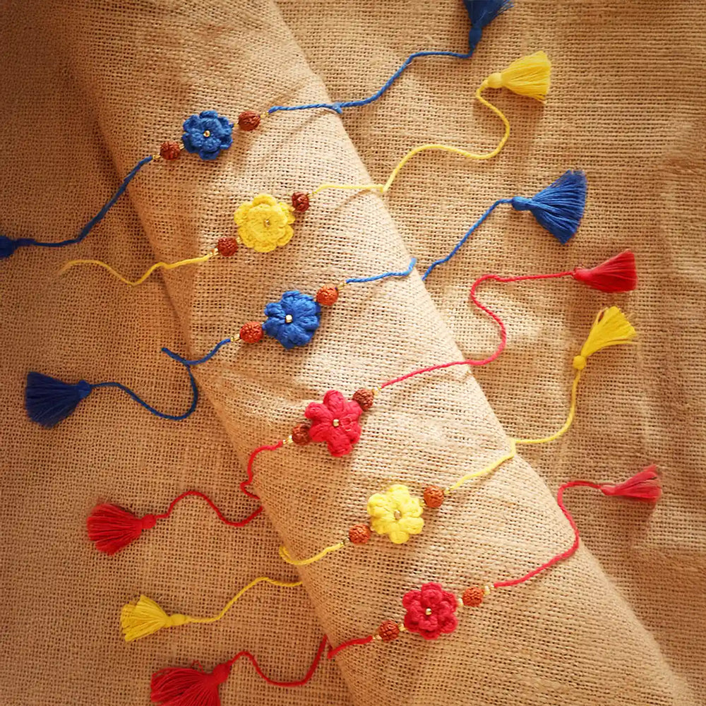 Handmade Crochet Flower And Rudraksh Rakhi With Roli Chawal Set Of 6 - Multiple Bracelets Laid Out