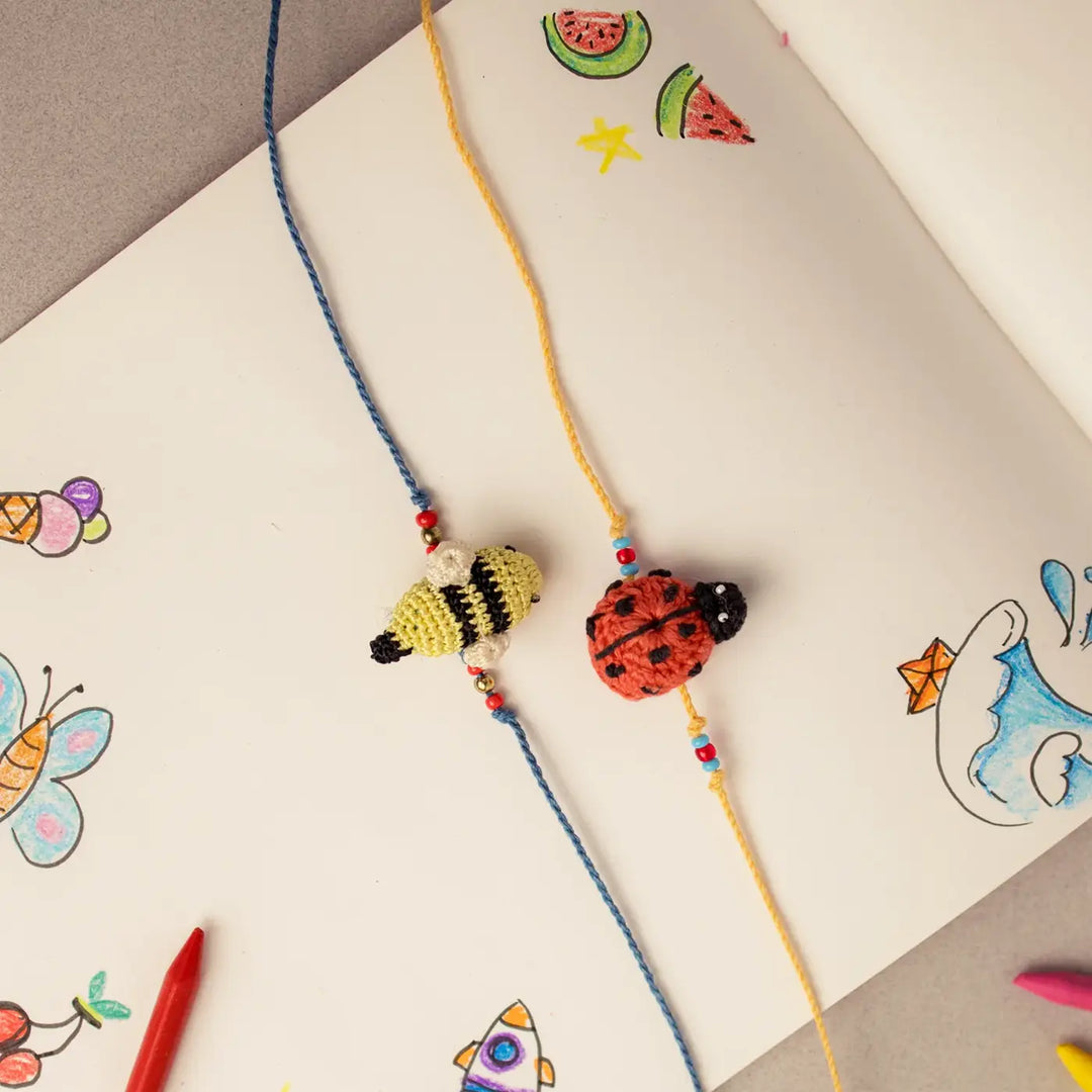 Handmade Crochet Beetle And Bee Theme Kids Rakhi With Roli Chawal Set Of 2 - Alternative Angle on Illustrated Background