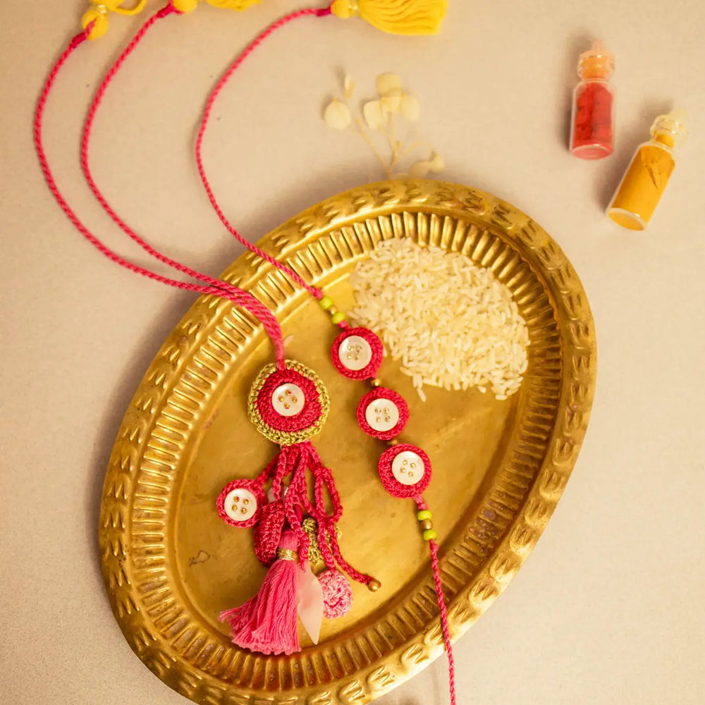 Handmade Crochet Pink Seepi Bhaiya Bhabhi Rakhi With Roli Chawal Set Of 2 - Styled on Decorative Plate