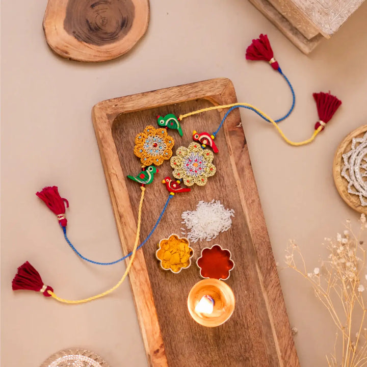 Handmade Crochet Flower And Birds Rakhi With Roli Chawal Set Of 2 - Decorative set with candle and tassels