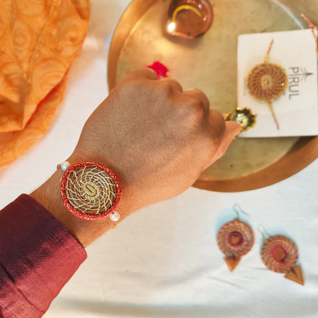 Eco Friendly Handmade Gold And Red Pine Needle Rakhi With Pouch And Roli Chawal - Wrist Shot