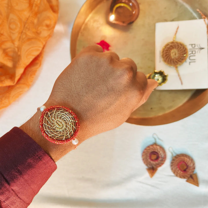 Eco Friendly Handmade Gold And Red Pine Needle Rakhi With Pouch And Roli Chawal - Wrist Shot