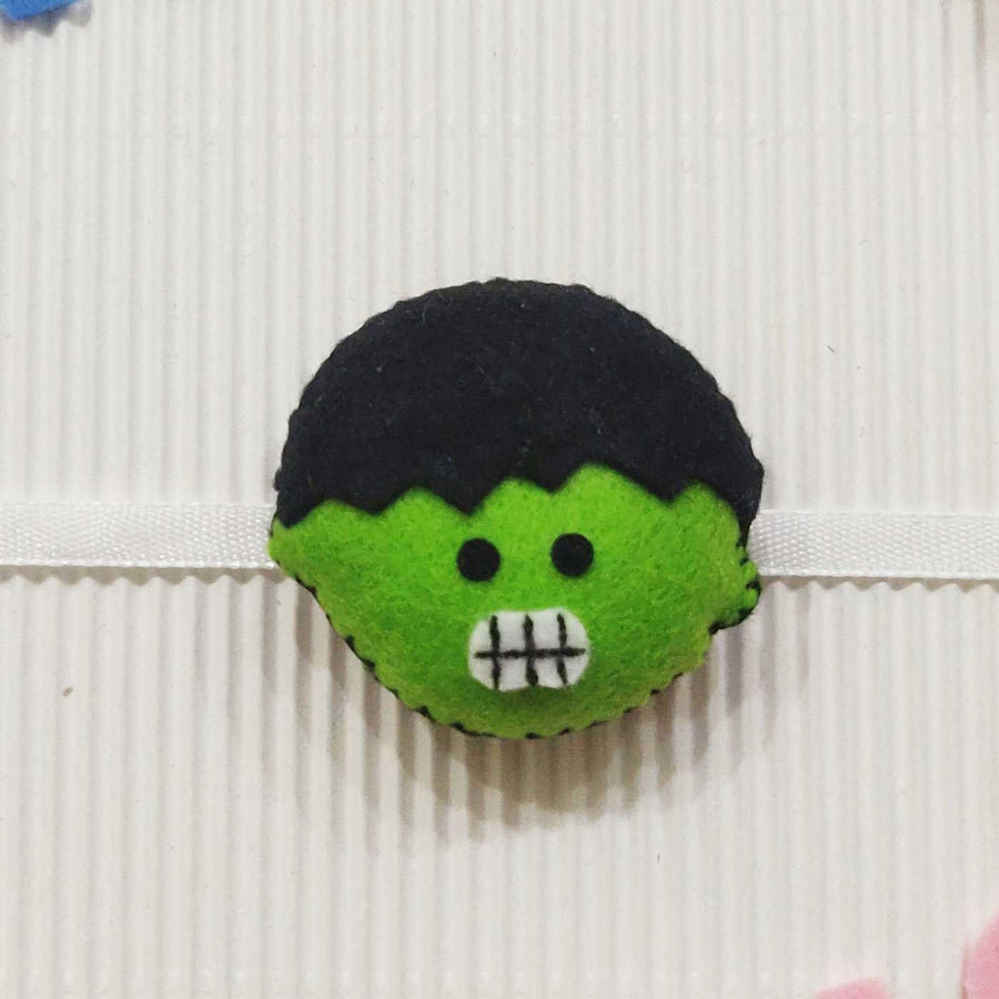 Handmade Hulk Theme Felt Kids Rakhi With Roli Chawal - Close-up of Green Character Brooch