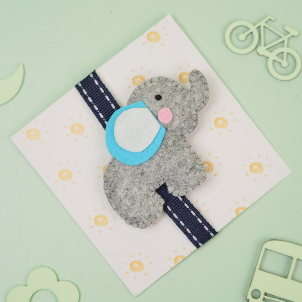 Handmade Elephant Theme Felt Kids Rakhi With Roli Chawal - Top View with Decorative Background