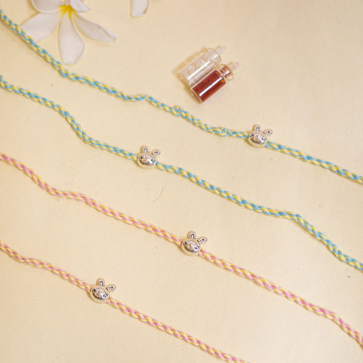 Handmade Silver Bunny Design Kids Rakhi With Roli Chawal - Flat lay showing multiple bracelets