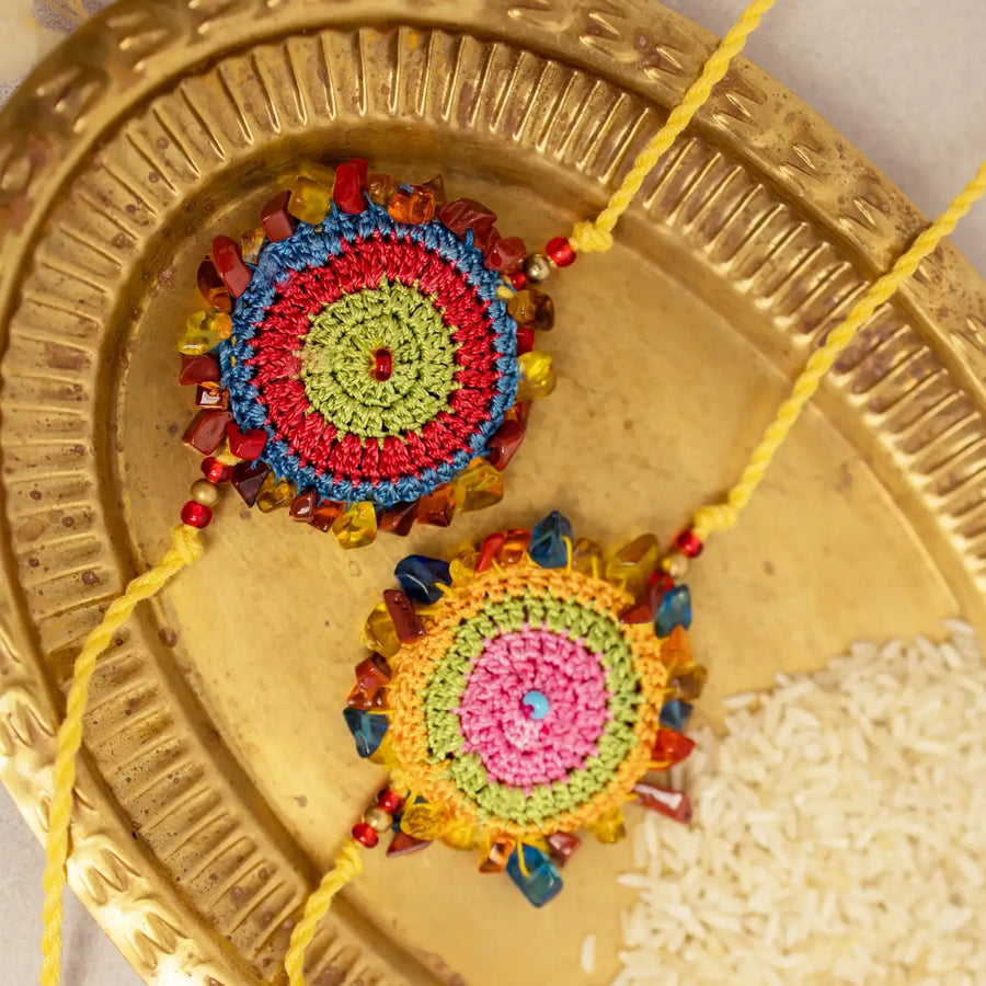 Handmade Crochet Multicolor Dhanak Rakhi With Roli Chawal Set Of 2 - Close-up of two rakhis