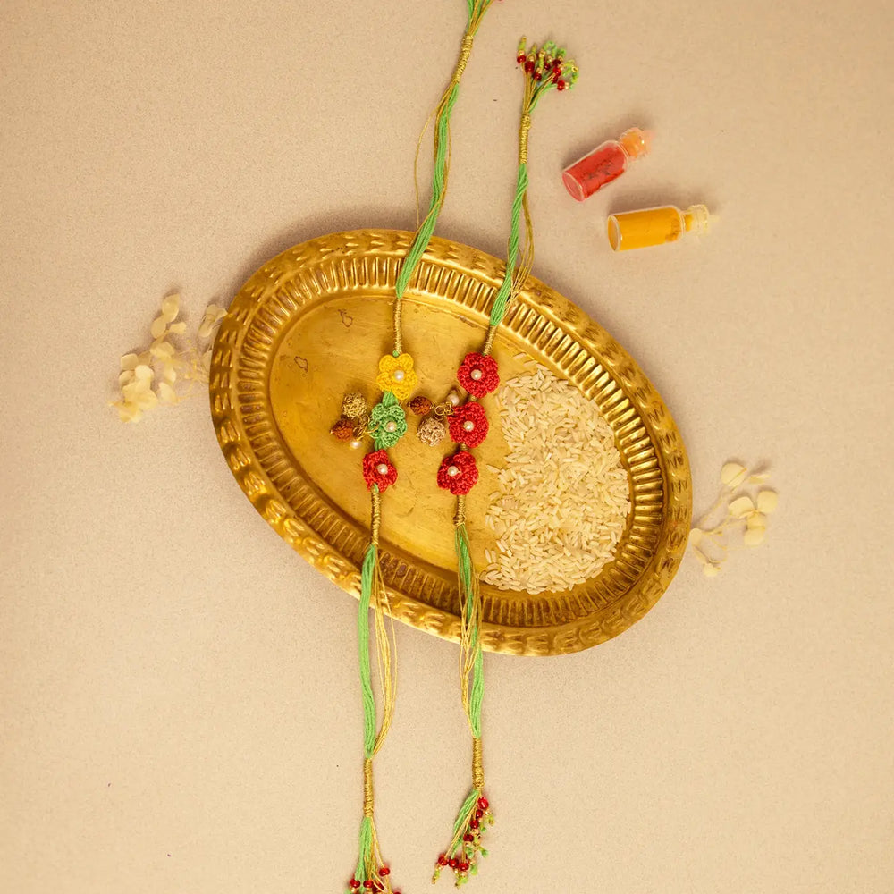 Handmade Crochet Ananya Phool And Rudraksh Rakhi With Roli Chawal Set Of 2 - Two Rakhis Arranged on Plate