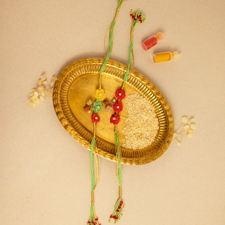 Handmade Crochet Ananya Phool And Rudraksh Rakhi With Roli Chawal Set Of 2 - Two Rakhis Arranged on Plate