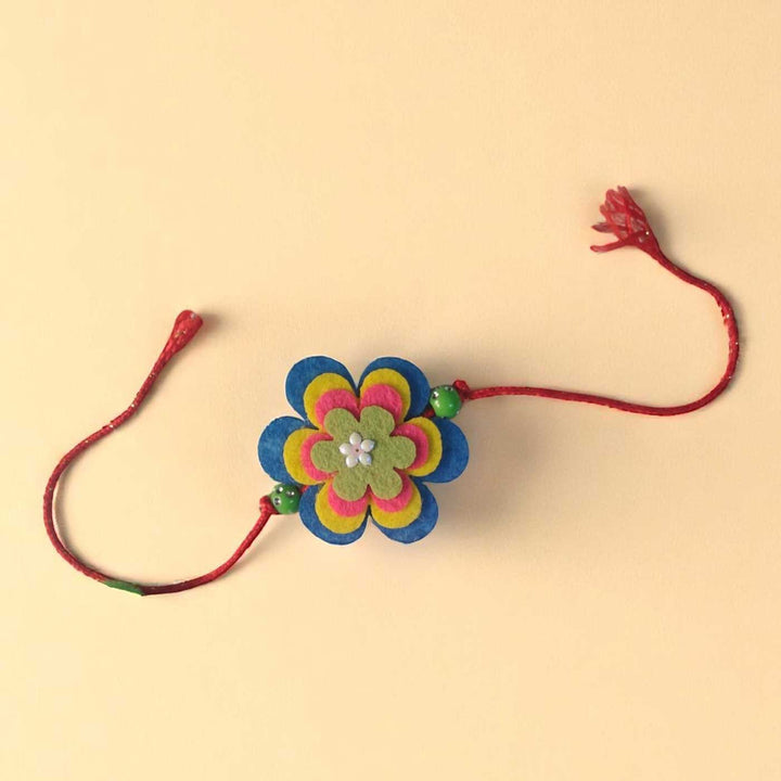 Handmade Beaded Flower Theme Pom Pom Felt Rakhi With Roli Chawal For Kids - Flat Lay Front View