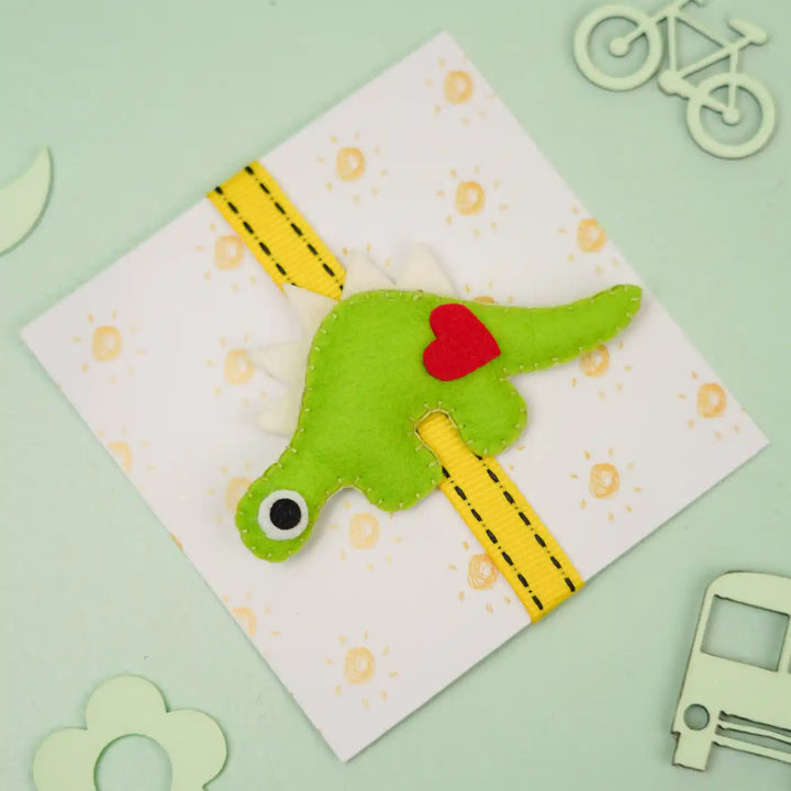 Handmade Dino Theme Felt Kids Rakhi With Roli Chawal - Front View with Props