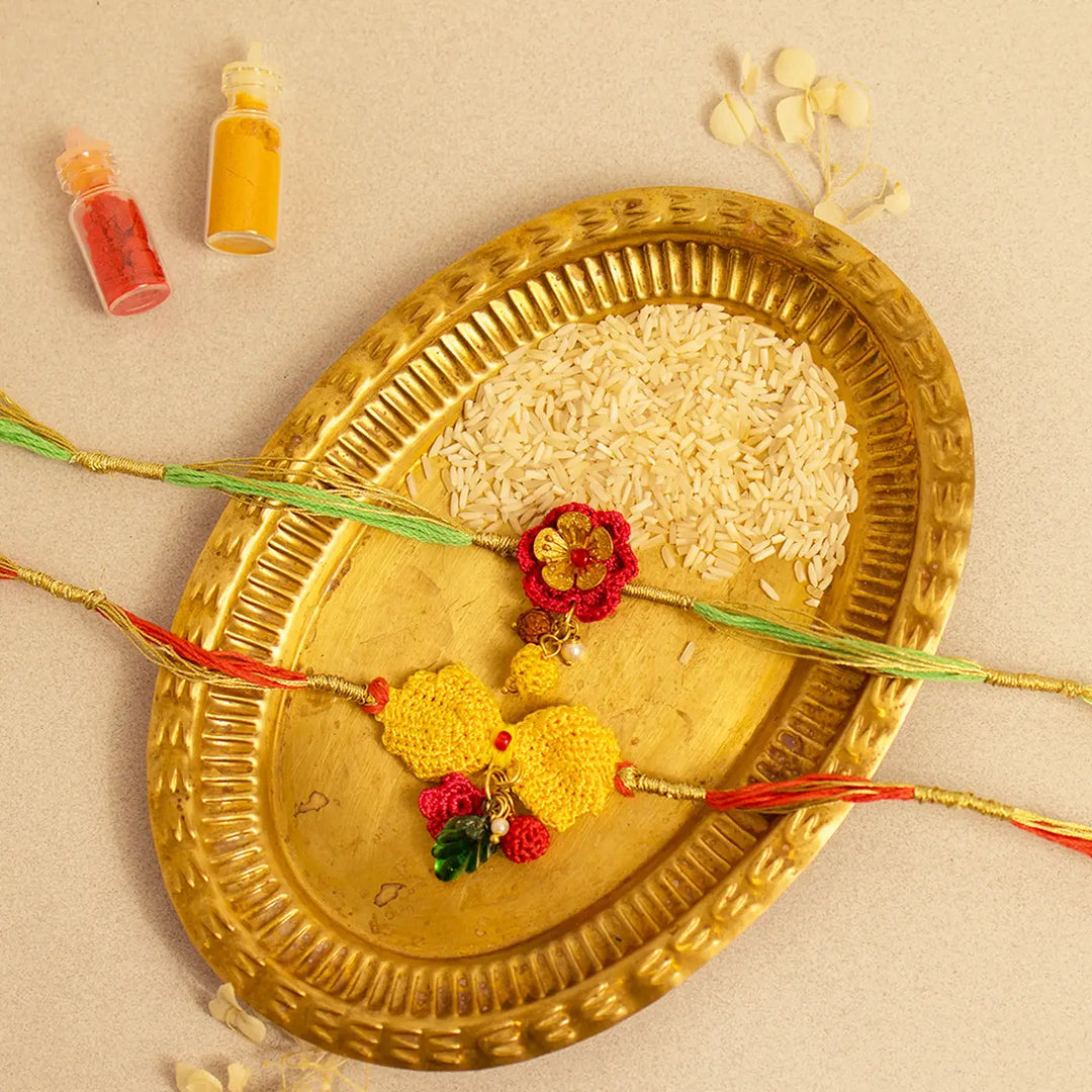 Handmade Crochet Ananya Golden Flower Rakhi With Roli Chawal Set Of 2 - Flat Lay with Color Powders