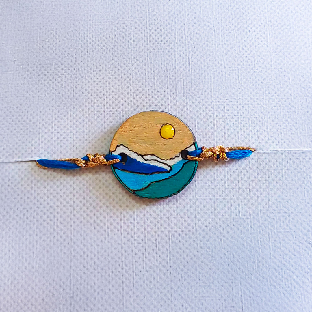 Handmade Mountain Sun And Snow Wooden Rakhi With Roli Chawal For Brother - Front View with Blue Thread