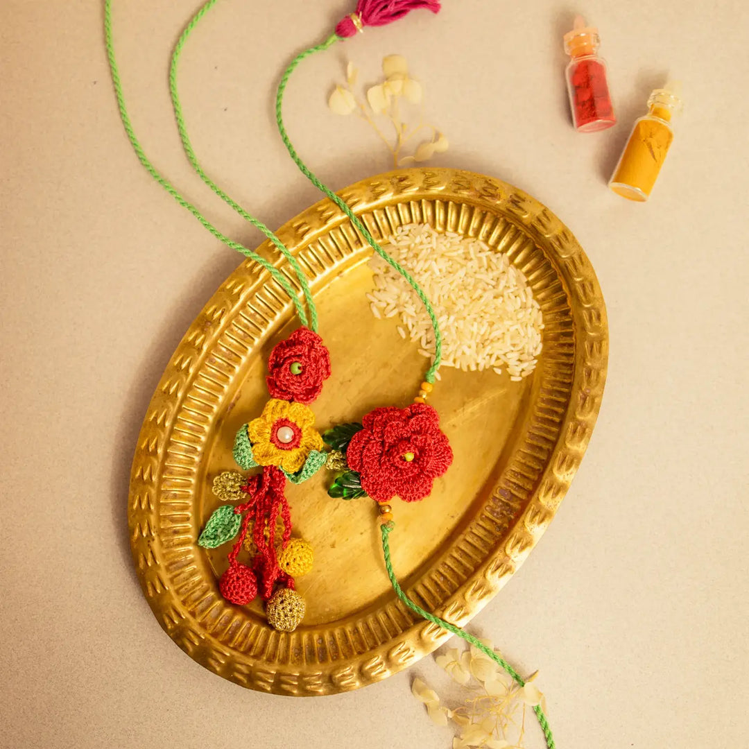 Handmade Crochet Surkh Gulab Bhaiya Bhabhi Rakhi With Roli Chawal Set Of 2 - Styled on brass platter with rice
