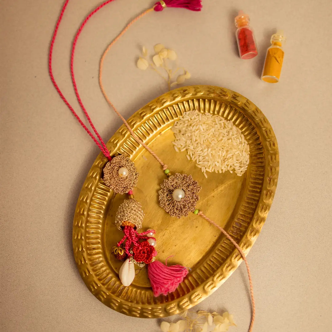 Handmade Crochet Moti Jhalar Bhaiya Bhabhi Rakhi With Roli Chawal Set Of 2 - Decorative tassels displayed on tray