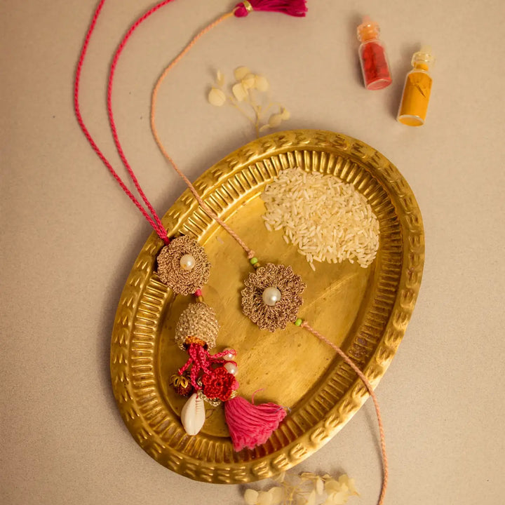 Handmade Crochet Moti Jhalar Bhaiya Bhabhi Rakhi With Roli Chawal Set Of 2 - Decorative tassels displayed on tray