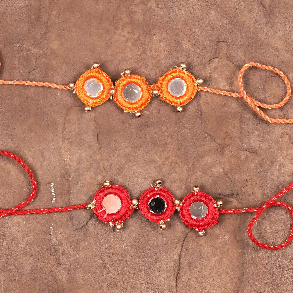 Handmade Mirror Work Red And Orange Rakhi With Roli Chawal Set Of 2 - Flat Lay Front View