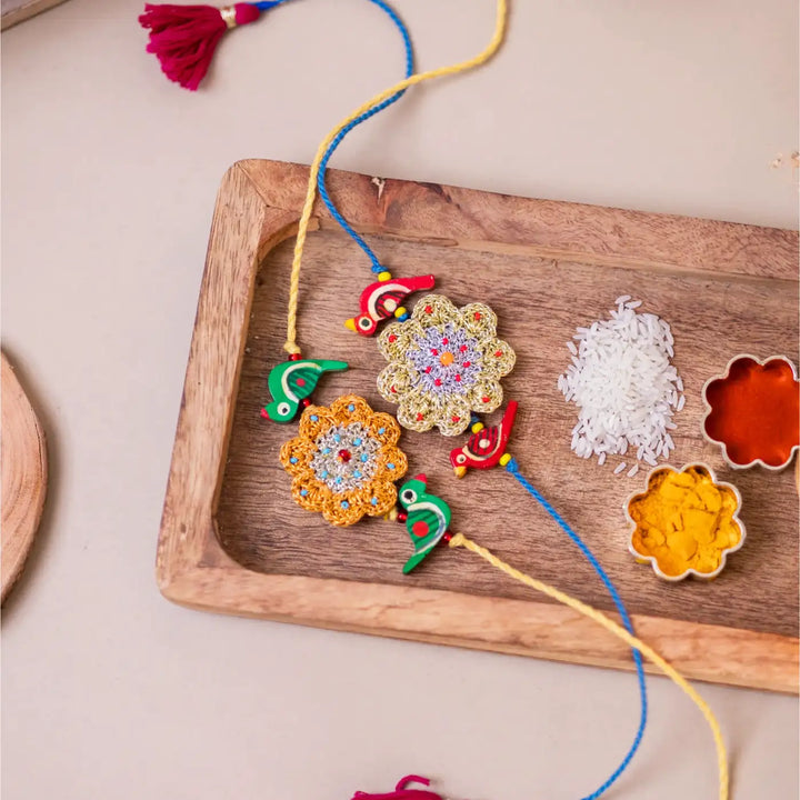 Handmade Crochet Flower And Birds Rakhi With Roli Chawal Set Of 2 - Decorative strings displayed on tray
