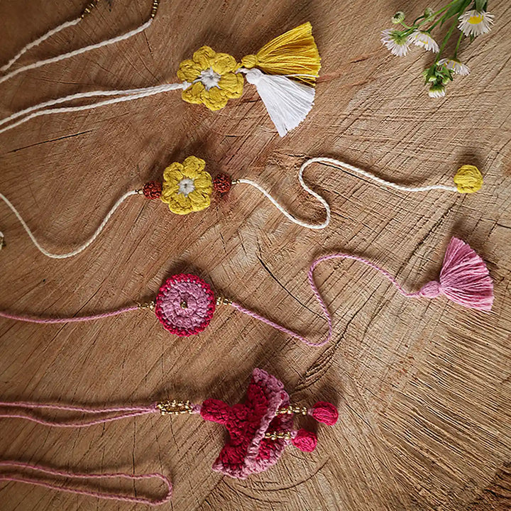 Handmade Crochet Pink And Yellow Bhaiya Bhabhi Rakhi With Roli Chawal Set Of 4 - Flat Lay with Focus on Texture