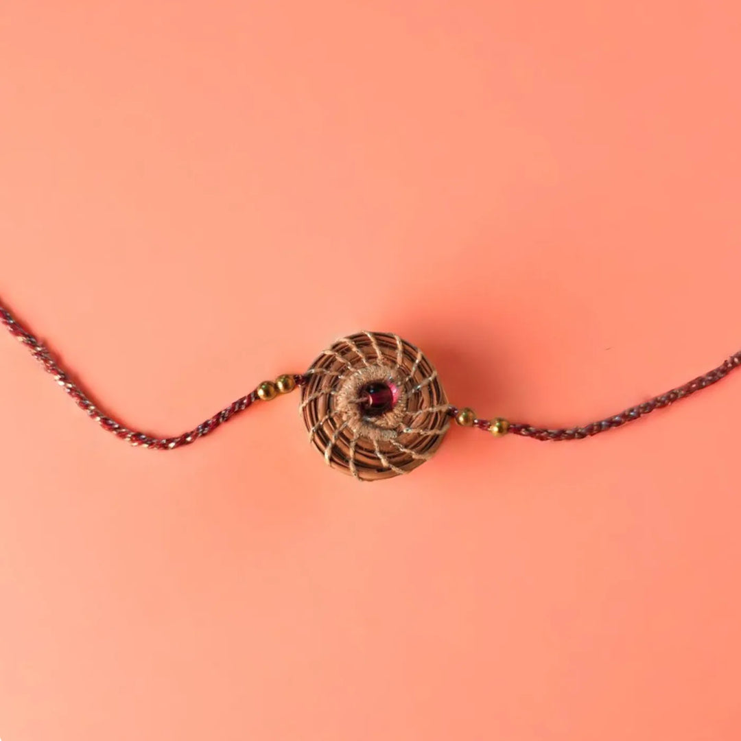 Eco Friendly Handmade Silver And Red Pine Needle Rakhi With Pouch And Roli Chawal - Flat Lay Centered View