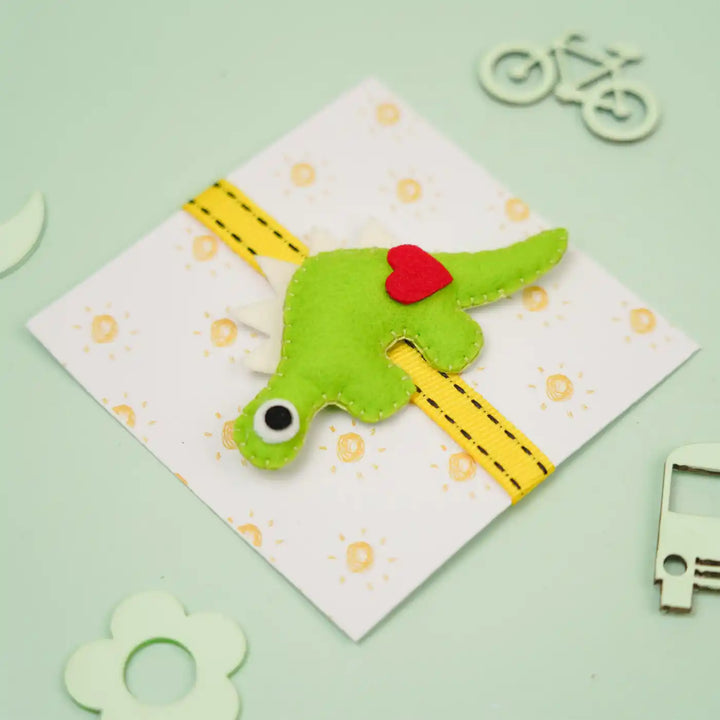 Handmade Dino Theme Felt Kids Rakhi With Roli Chawal - Front View with Props (7)
