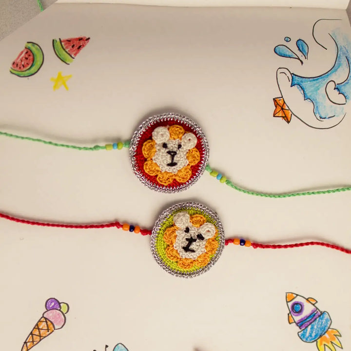 Handmade Crochet Lion Theme Kids Rakhi With Roli Chawal Set Of 2 - Close-up Wristband Detail with Sketchbook