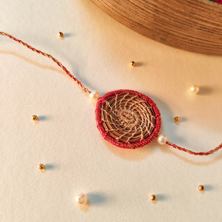 Eco Friendly Handmade Gold And Red Pine Needle Rakhi With Pouch And Roli Chawal - Styled Flat Lay with Pearls and Beads