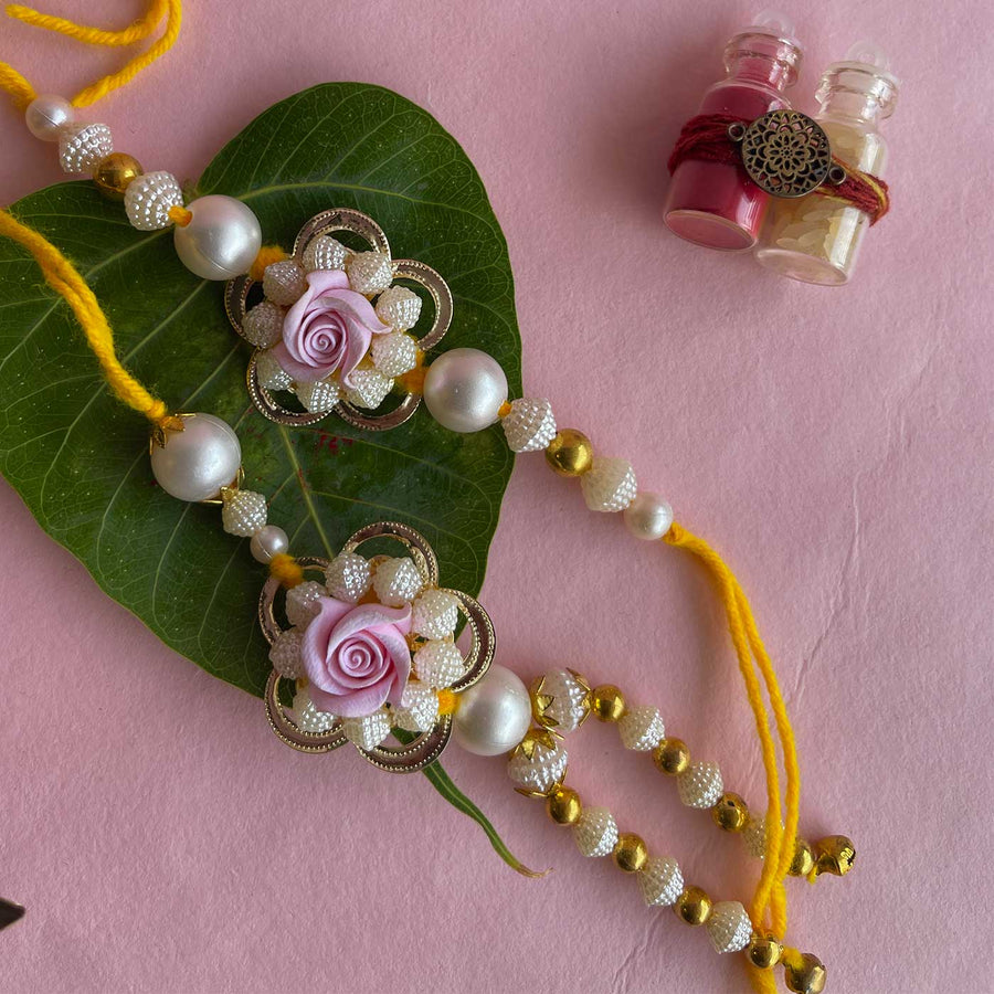 Handmade Purple Flower Design Pearl And Stone Bhaiya Bhabhi Rakhi - Full View with Leaf Background
