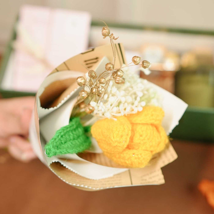 Personalized Handmade Crochet Flower Lover Rakhi Hamper Includes 1 Gift Box 1 Crochet Flower 1 Rakhis 1 Roli Chawal 1 Candle And 1 Message Card - Hand Holding Flower Bunch