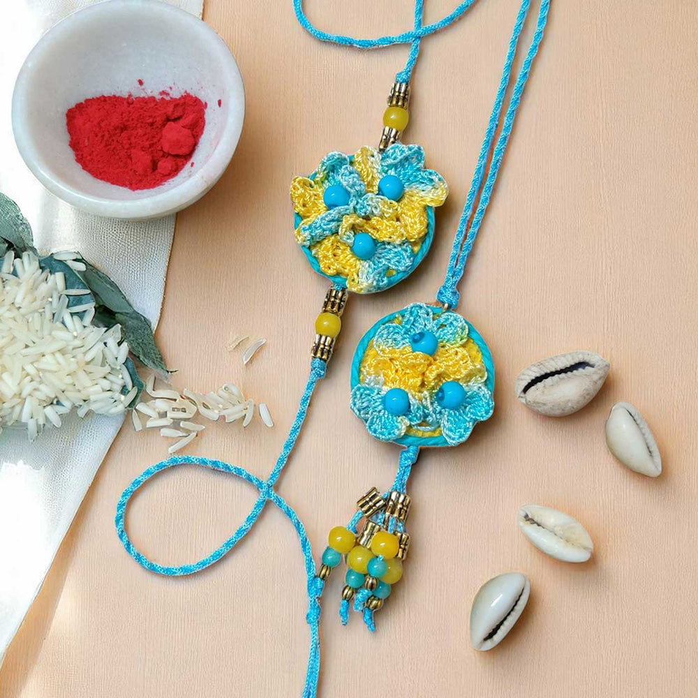 Handmade Crochet Beaded Flower Theme Cotton Rakhi With Roli Chawal For Bhaiya And Bhabhi - Top-down with Scattered Rice and Shells
