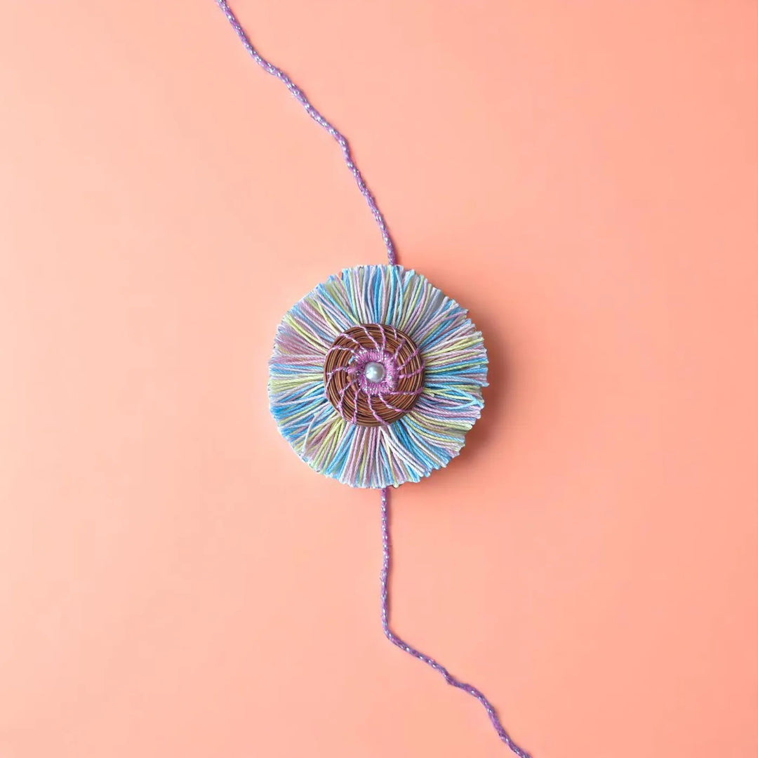 Eco Friendly Handmade Pastel Colour Pine Needle Rakhi With Pouch And Roli Chawal - Flat Lay on Pink Surface