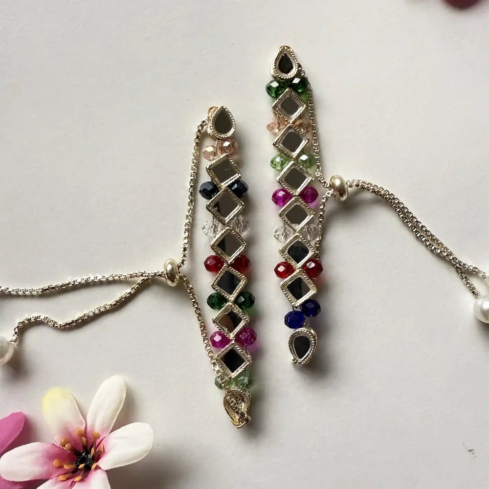 Handmade Mirror Work Lumba Bracelet Rakhi For Bhabhi With Roli Chawal - Flat Lay with Floral Accent