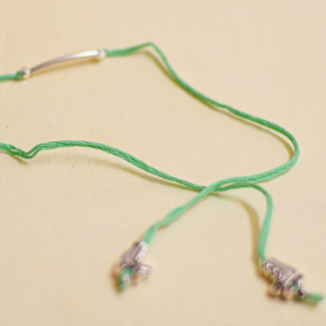 Handmade Stake Board Shoe And Pearl Design Rakhi With Roli Chawal - Green bracelet flat lay