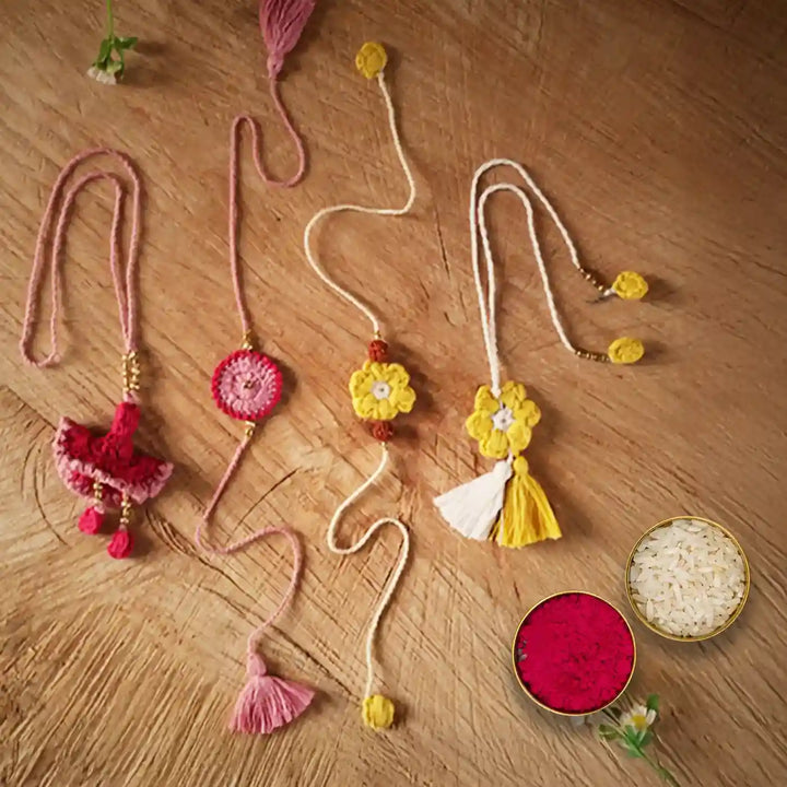 Handmade Crochet Pink And Yellow Bhaiya Bhabhi Rakhi With Roli Chawal Set Of 4 - Flat Lay Display