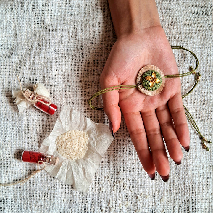 Handmade Papier Mache Floral Green Rakhi With Roli Chawal - Rakhi Displayed on Hand with Items