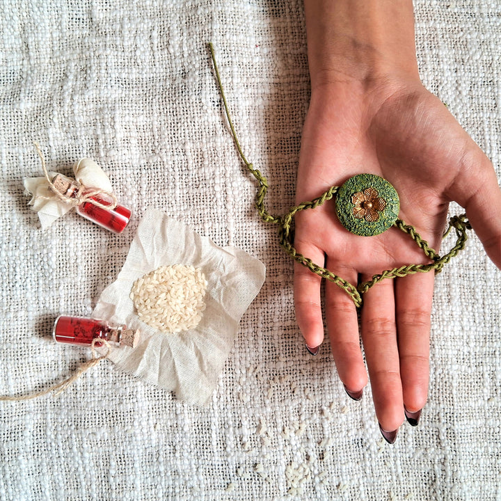 Handmade Papier Mache Green With Rustic Flower Rakhi With Roli Chawal - Handheld View with Complementary Items