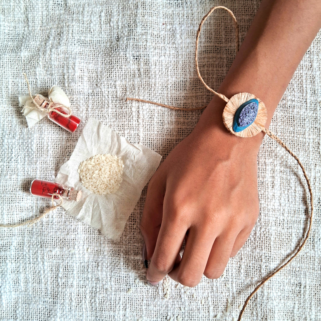 Handmade Papier Mache Naquashi Blue Rakhi With Roli Chawal - Worn on wrist display