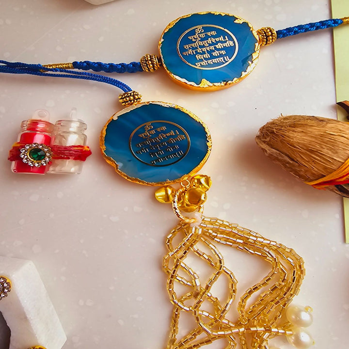 Handmade Gayatri Mantra Agate Bhaiya Bhabhi Rakhi With Roli Chawal - Close-up of blue Rakhi with golden tassels