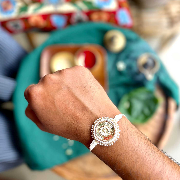 Handmade Zardozi White And Golden Rakhi With Wooden Box And Roli Chawal - Worn on Wrist Close-up