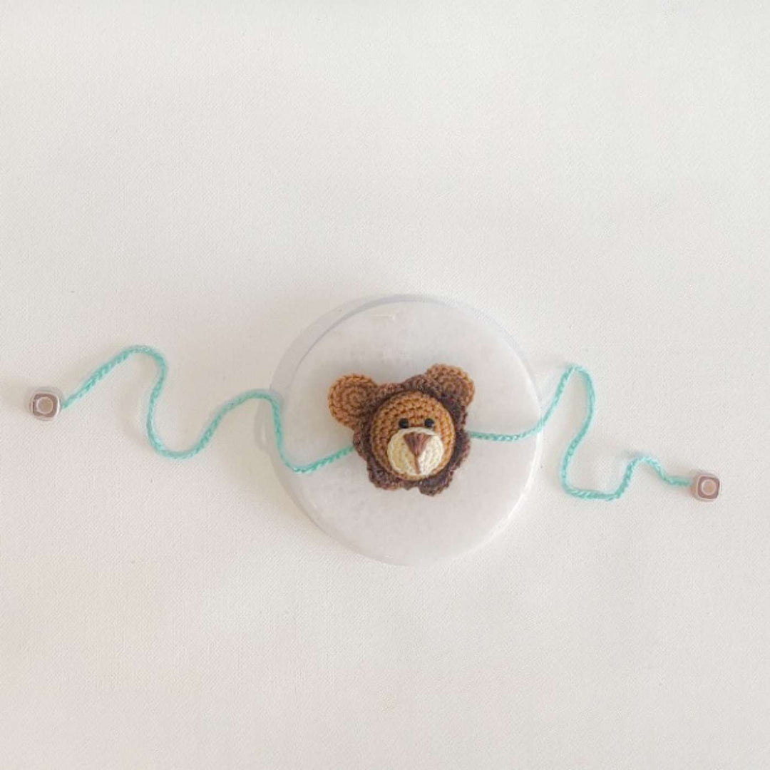 Handmade Crochet Lion Cub Kids Rakhi With Roli Chawal - Flat Lay with Accessories