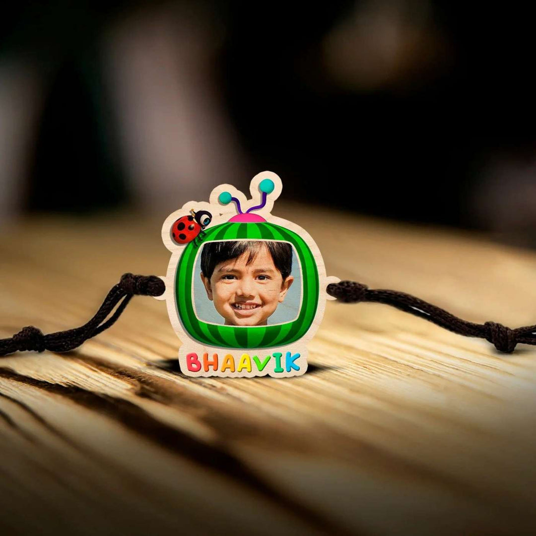 Photo Personalized Handmade Cocomelon Wooden Kids Rakhi With Roli Chawal - Front View on Wooden Surface