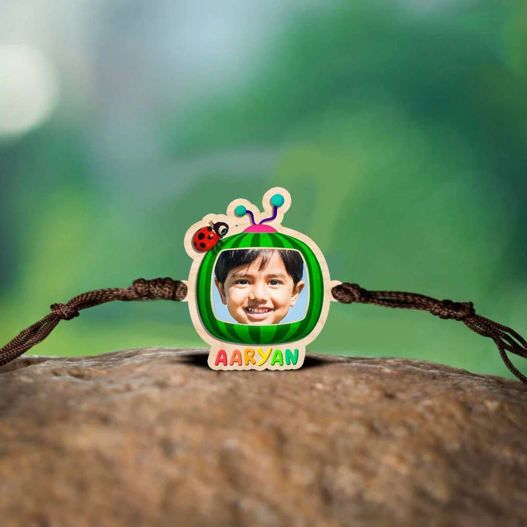 Photo Personalized Handmade Cocomelon Wooden Kids Rakhi With Roli Chawal - Front View on Natural Surface