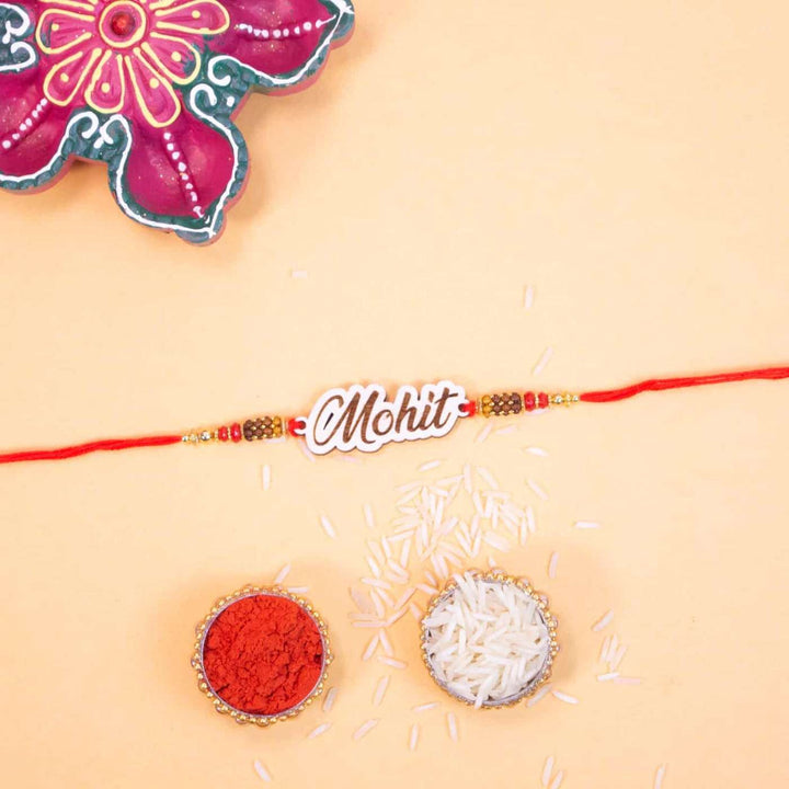 Personalized Handmade Engraved Name Wooden Rakhi With Roli Chawal - Flat Lay with Festival Items