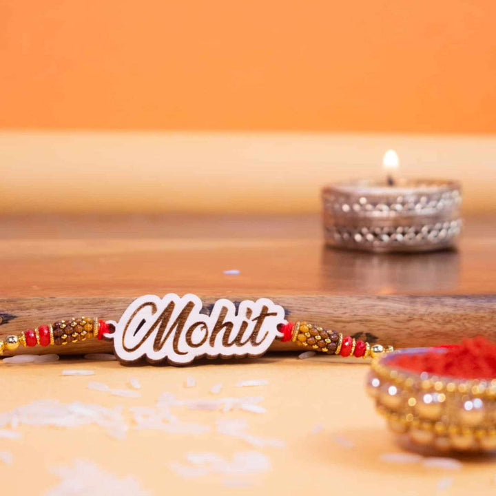 Personalized Handmade Engraved Name Wooden Rakhi With Roli Chawal - On Surface with Lit Diya